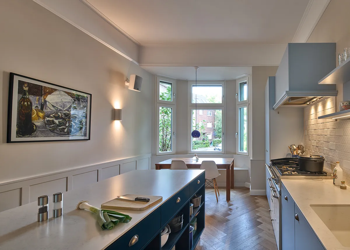 Offene Küche im Umbau einer Maisonettewohnung mit hellblauen Fronten, zentraler Kochinsel und hochwertigem Gasherd im klassischen Stil.